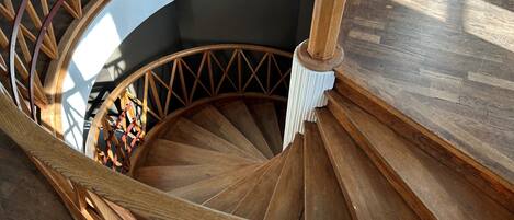 A wooden spiral staircase with a white railing and a wooden handrail.