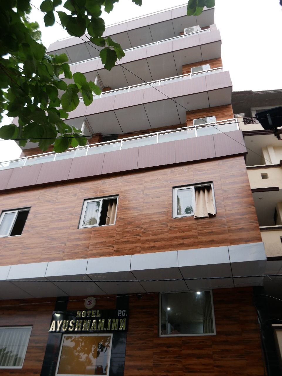 A multi-story building with a sign for "HOTEL AYUSHMAN INN."