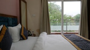 Quarto de hotel com cama, janela grande e vista para a água.