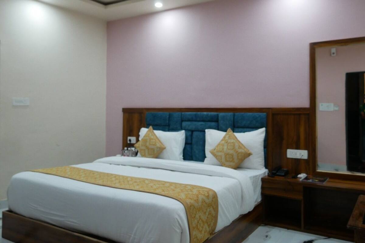 Habitación de hotel con una cama grande, cabecera de madera y mesita de noche con teléfono y lámpara.