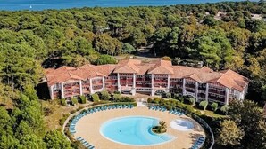 Un resort con una gran piscina circular, varios balcones y vista al mar.