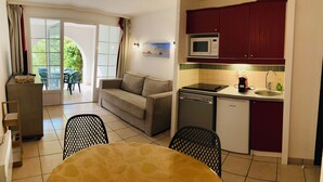 Una cocina compacta equipada con microondas y lavavajillas, y una zona de comedor con mesa y sillas.