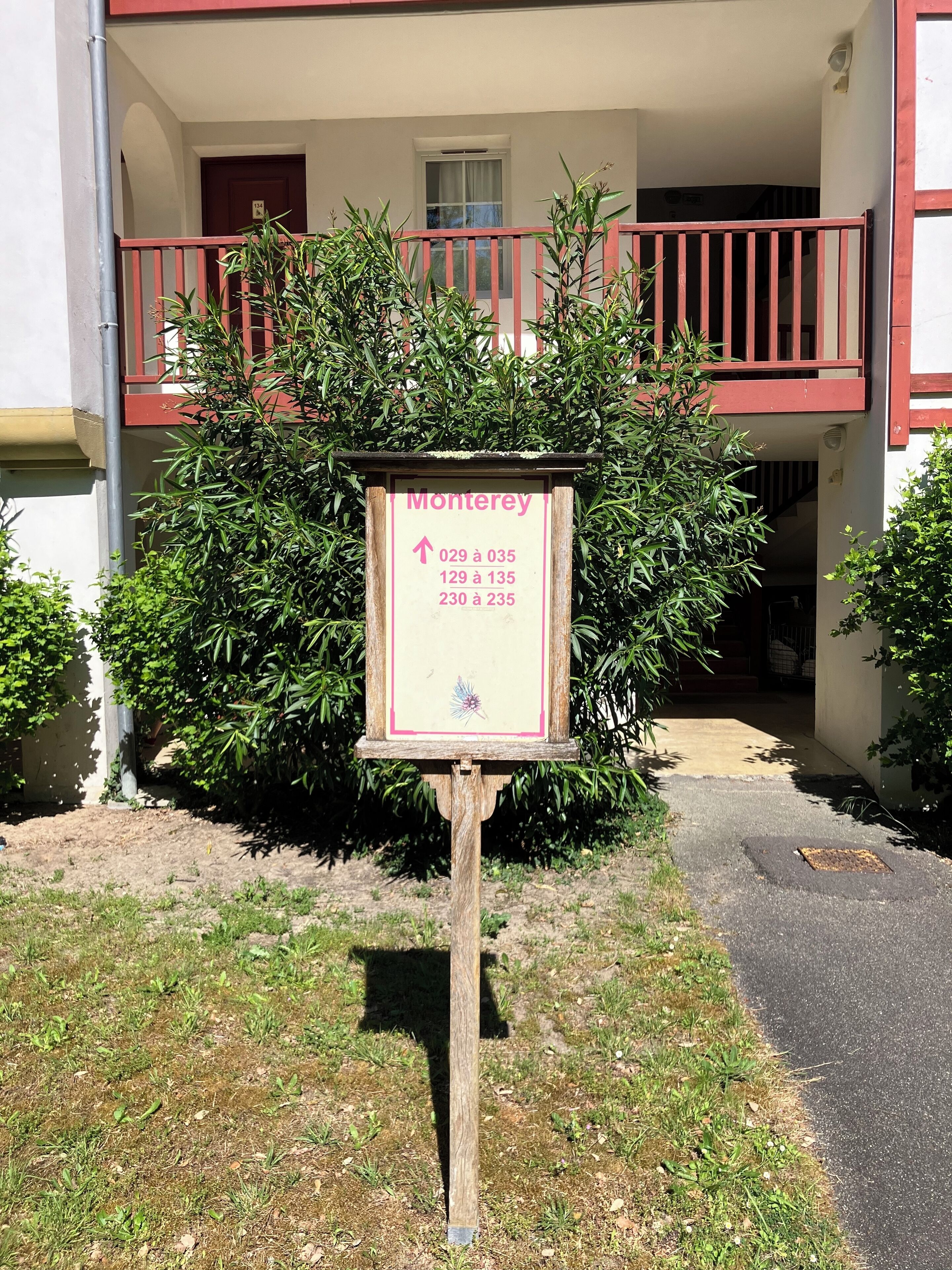 A sign with room numbers and directions for a building with a red balcony.