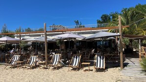 Un restaurante frente a la playa con terraza y sombrillas.