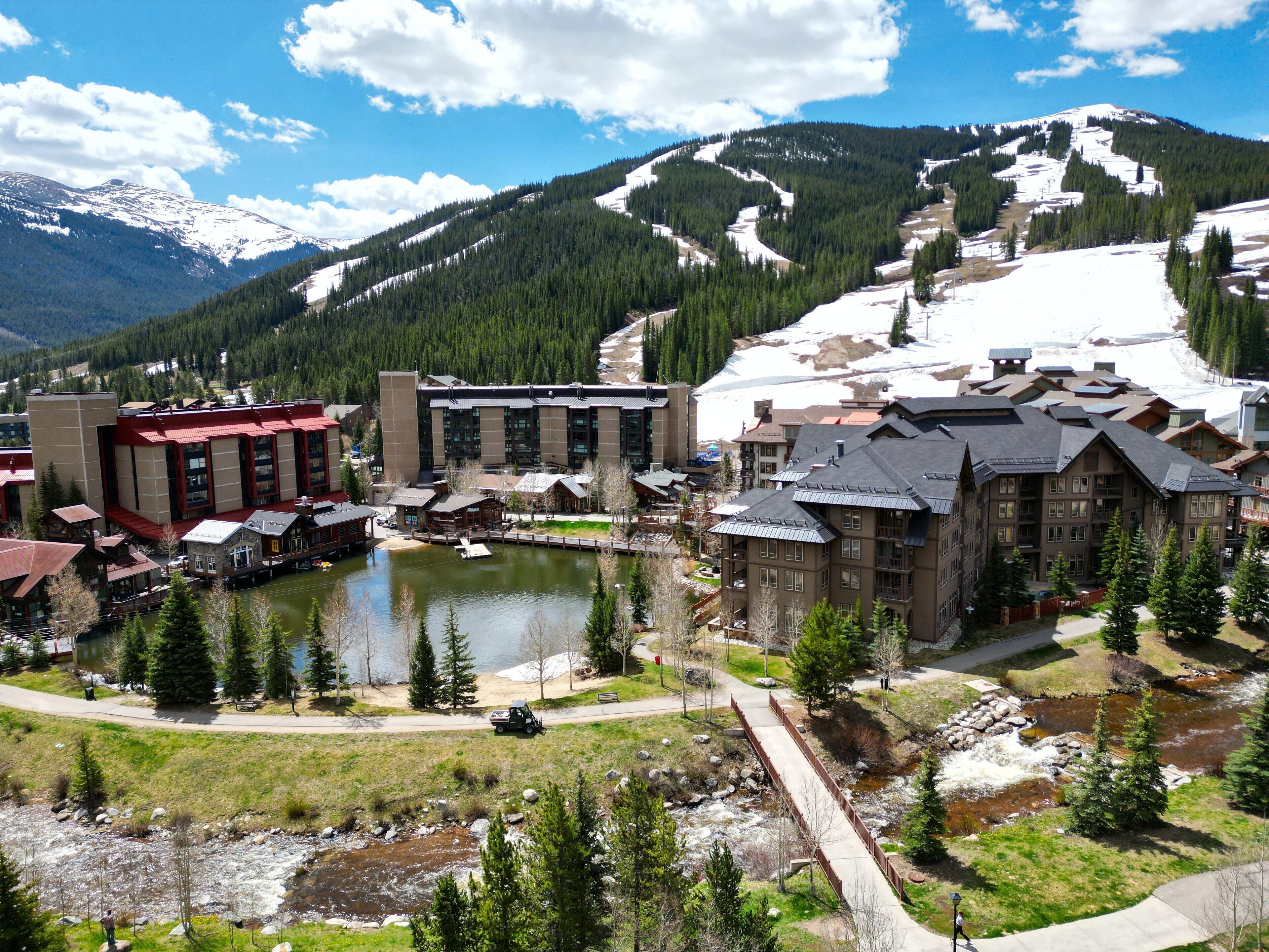 Un resort con un lago, edificios y una montaña al fondo.