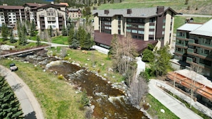 A hotel complex with multiple buildings, a river, and a mountainous backdrop. - SkyRun Copper Mountain Resort Vacation Lodging (Copper Mountain)
