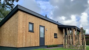 Ein modernes Holzgebäude mit flachem Dach, einer Tür und zwei Fenstern.