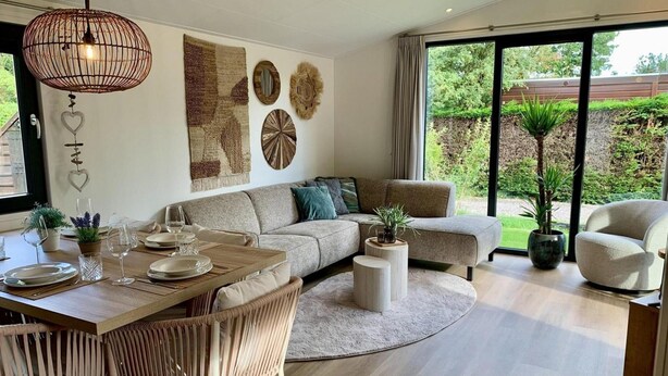 Ein modernes Wohnzimmer mit Essbereich, ausgestattet mit einer großen Couch, einem Couchtisch und einem Esstisch für vier Personen.