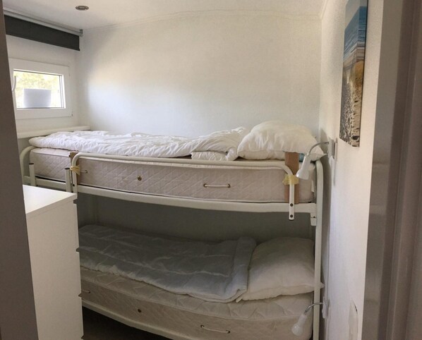 A bunk bed room with a window, a bedside table, and a wall-mounted lamp. - Beautiful Bungalow in North Holland (Sint Maartensvlotbrug)
