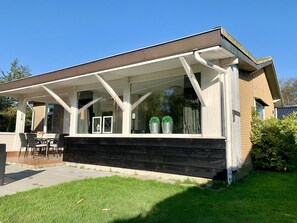 A modern house with a covered patio, a dining area, and a small garden. - Holiday Home With a Sunny Garden (Sint Maartensvlotbrug)