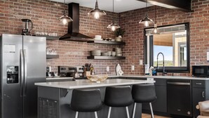 Uma cozinha moderna com parede de tijolos, eletrodomésticos de aço inoxidável e uma ilha grande com banquetas.