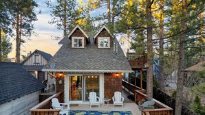 A cabin with a deck, two white Adirondack chairs, and a blue floral rug.