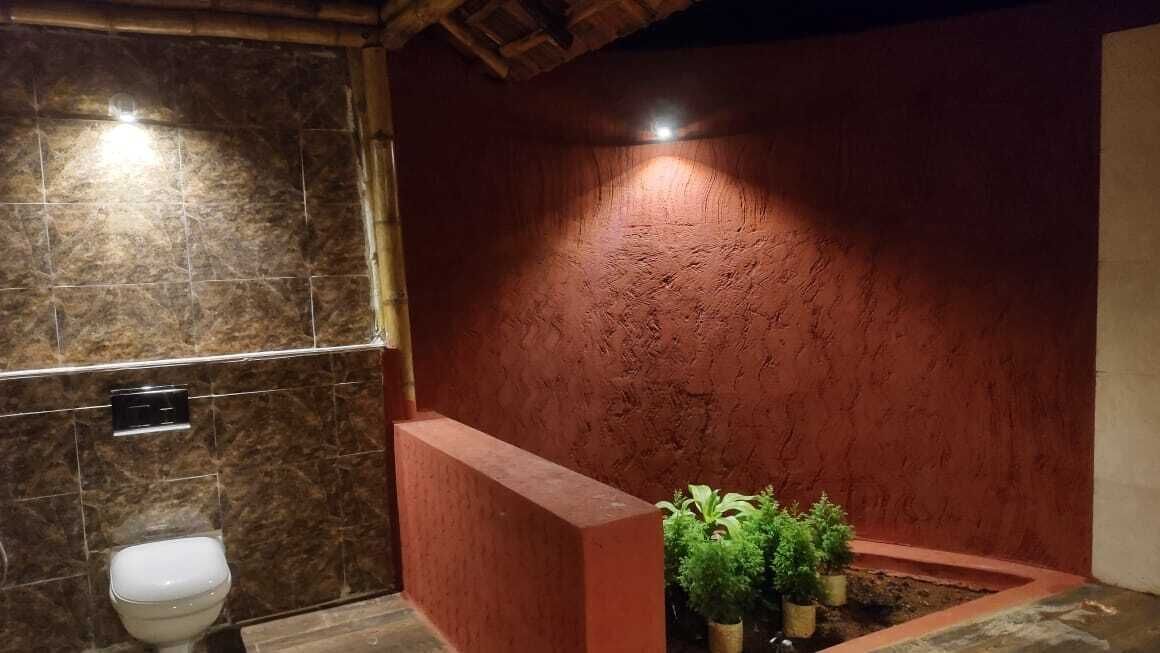 A bathroom with a marble wall, a red accent wall, a toilet, and a small planter with plants.