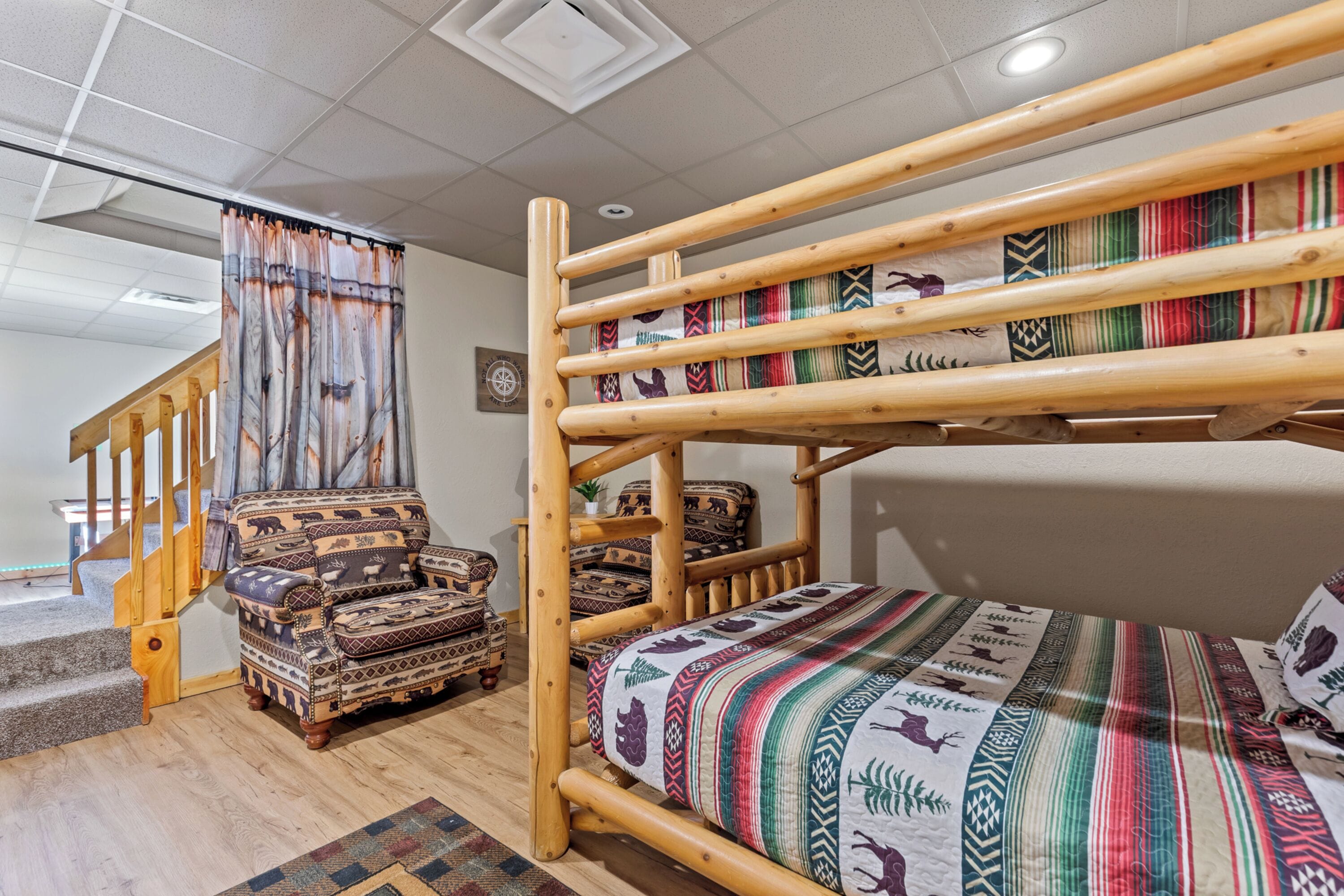 Una habitación con una cama litera, una silla de madera y una escalera.