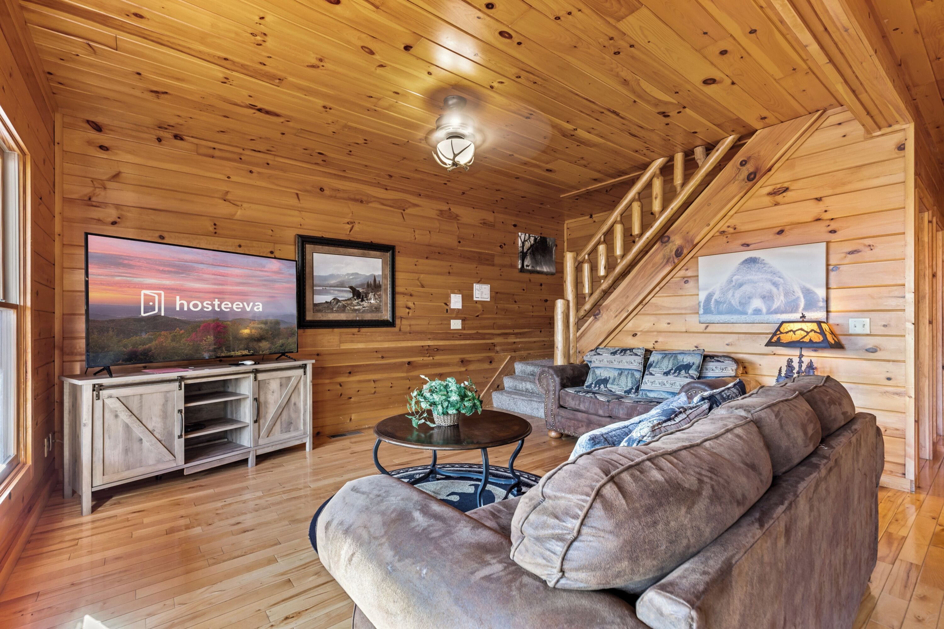 A wooden interior with a sofa, TV, and staircase.