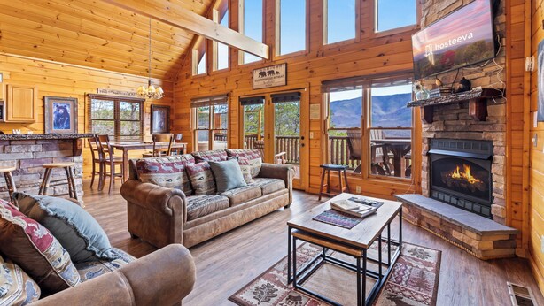 Eine großzügige Lodge mit geräumigem Wohnbereich, der einen Kamin, Holzwände und große Fenster mit Blick auf die Berge bietet.