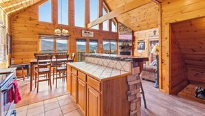 Ein Holzblockhaus-Interieur mit Küche, Essbereich und einer Bar.