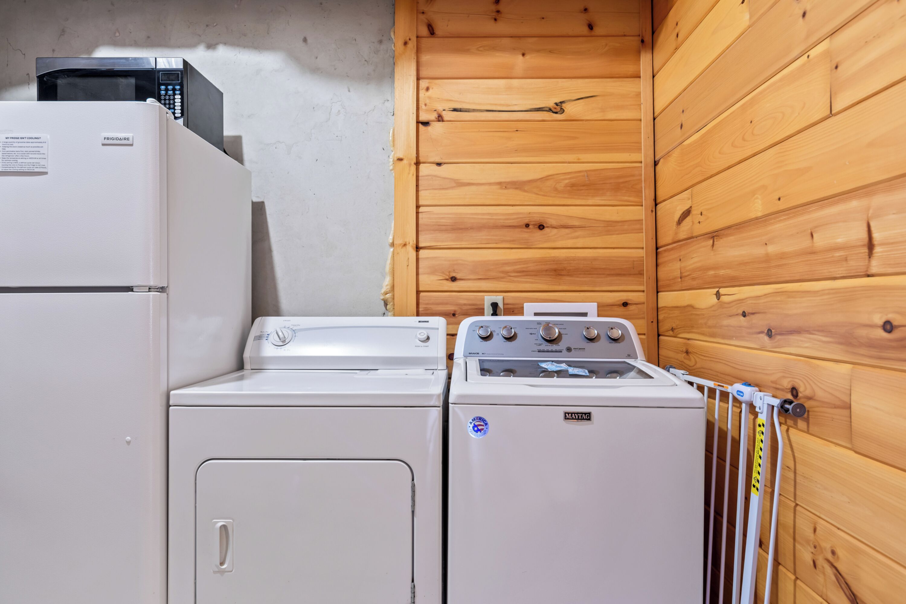 Un espace buanderie compact comprenant un réfrigérateur blanc, un lave-linge et un sèche-linge.