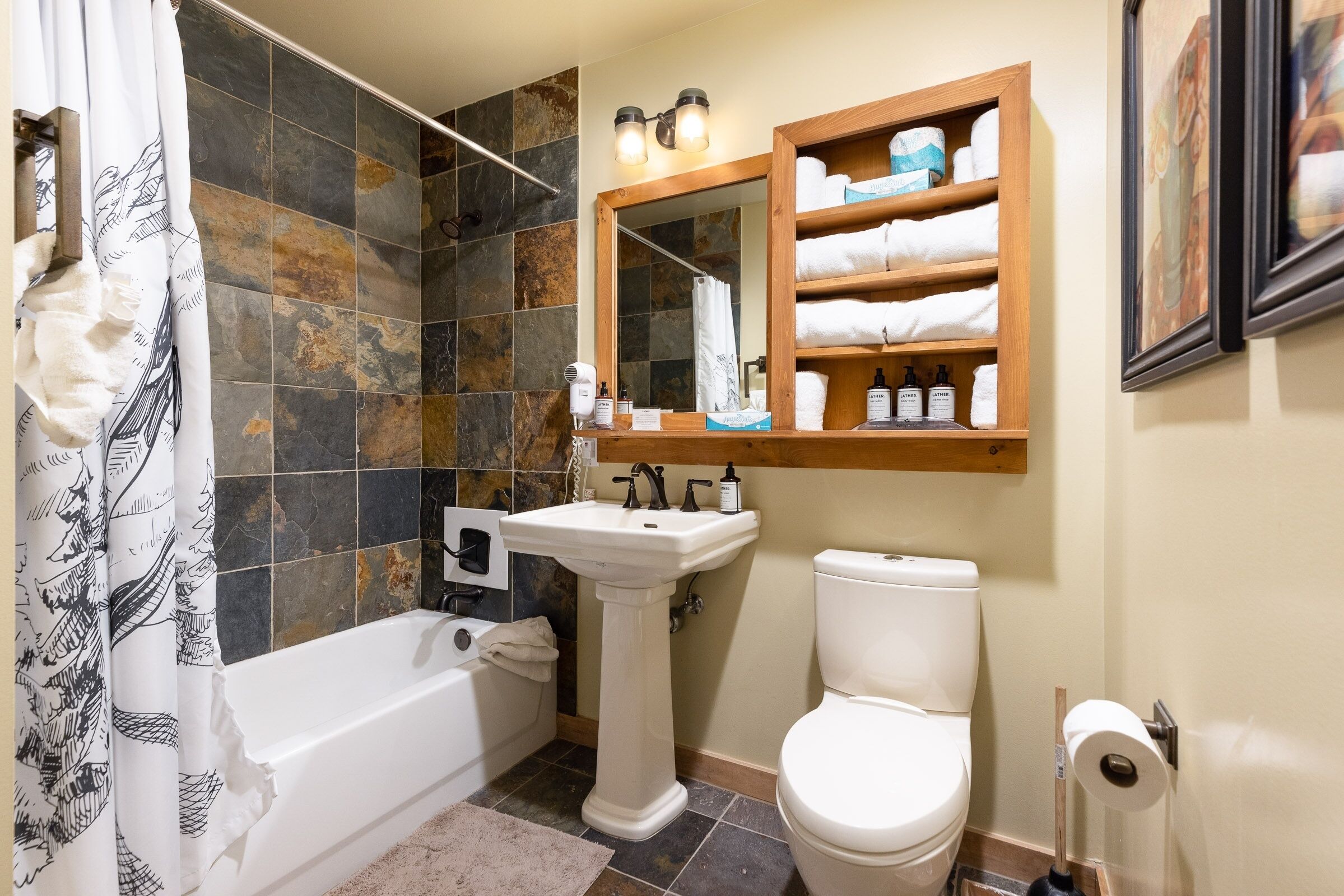 A bathroom with a bathtub, a pedestal sink, a toilet, and a shower area.