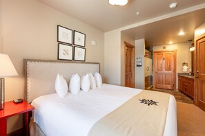 A hotel room with a large bed, a red nightstand, and a wooden wardrobe.