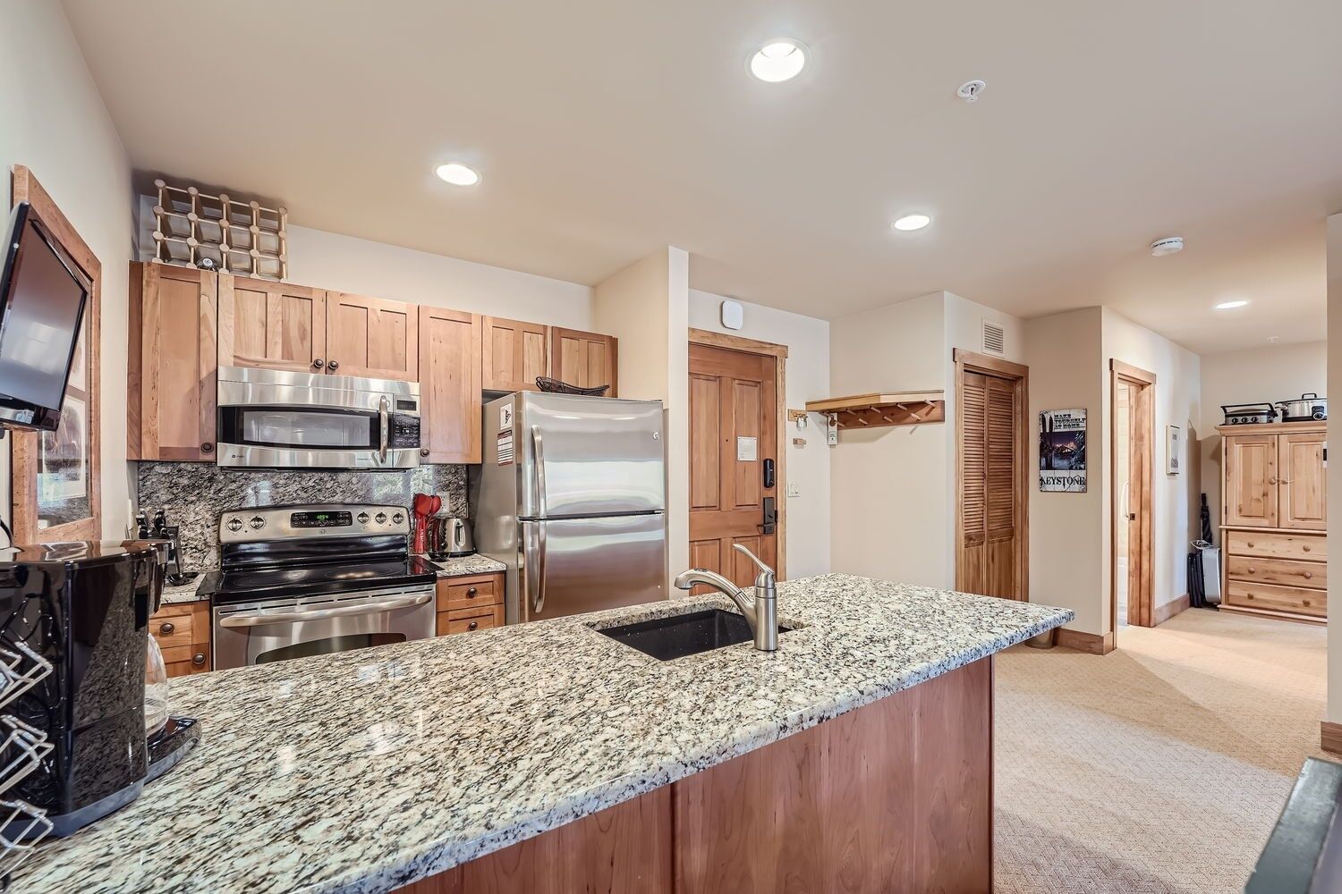 A modern kitchen with granite countertops, stainless steel appliances, wooden cabinets, and a built-in oven.