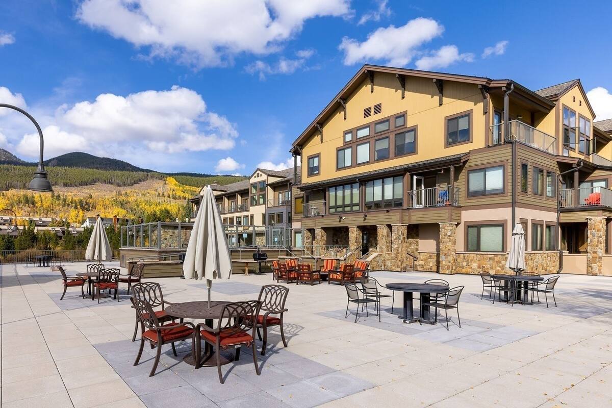 A hotel with outdoor seating, stone facade, and multiple balconies.