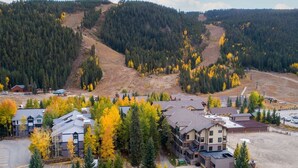 A residential area with multiple two-story houses, a parking lot, and a forested hillside in the background. - Keystone Ski Resort CO - Slopeside Lodging (Keystone)