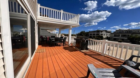 A wooden deck with outdoor furniture, a grill, and a covered seating area.