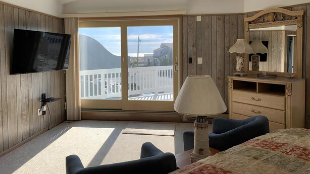 Une chambre d’hôtel équipée d’une télévision, d’un balcon avec vue, d’un bureau avec une lampe et d’une commode.
