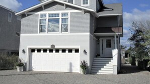 Une maison à deux étages avec un garage, un porche à l’avant et un escalier menant à l’entrée.