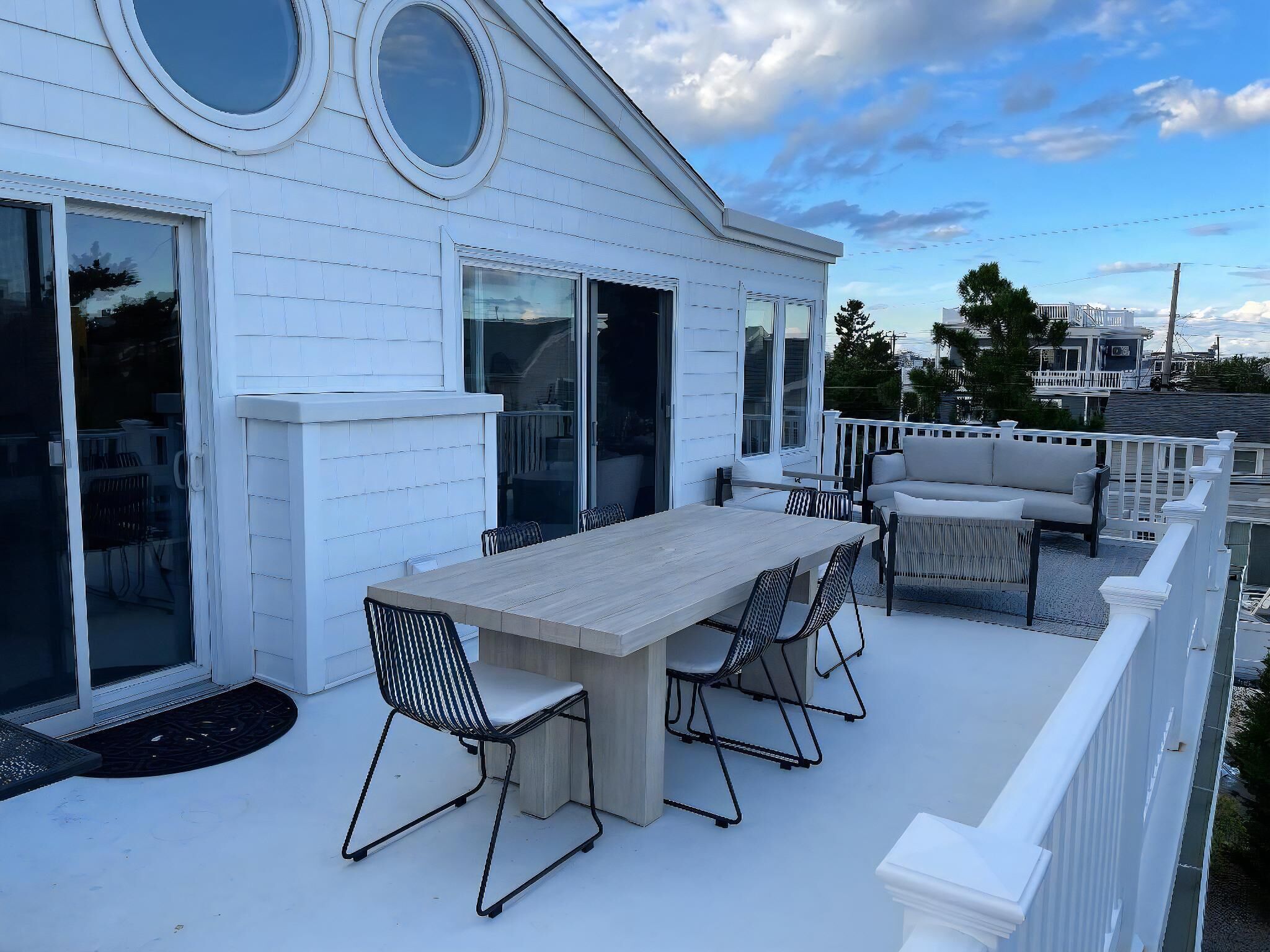 A white house with a covered patio, a dining table with chairs, and a sofa.