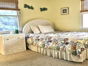 Una camera da letto con un letto, una cassettiera, una finestra e una decorazione a parete.
