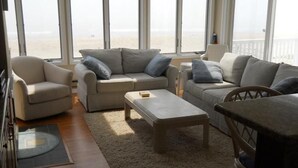 Una sala de estar con un sofá, una mesa de centro y vista a la playa.