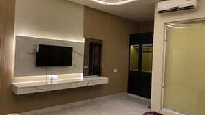 Une salle de bain moderne avec un meuble-lavabo en marbre, un téléviseur fixé au mur et une douche à l’italienne.
