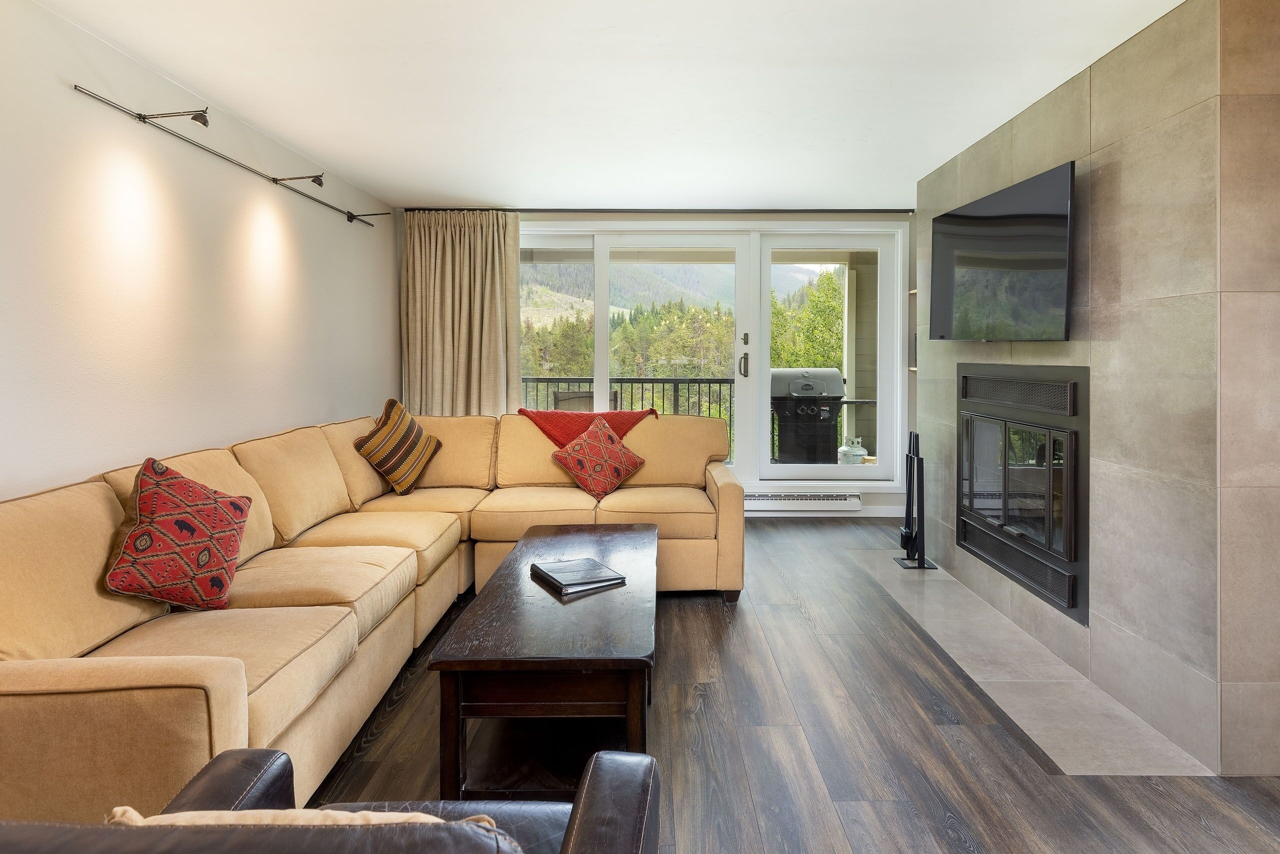 A modern living room with a sectional sofa, a coffee table, and a fireplace.