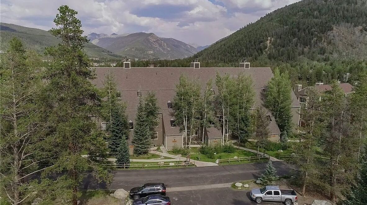 A residential area with houses, a paved road, and a mountain backdrop.