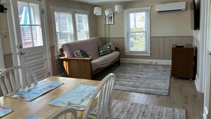 A cozy living room with a sofa, a dining table with chairs, and a wooden cabinet. - Nice clean rear cottage just 3 homes to the beach in Ship Bottom (Ship Bottom)
