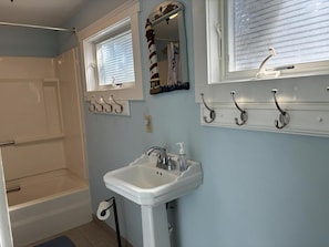 A bathroom with a bathtub, a sink, and a mirror.