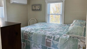 A bedroom with a bed, a chair, a dresser, a window, and an air conditioning unit. - Nice clean rear cottage just 3 homes to the beach in Ship Bottom (Ship Bottom)