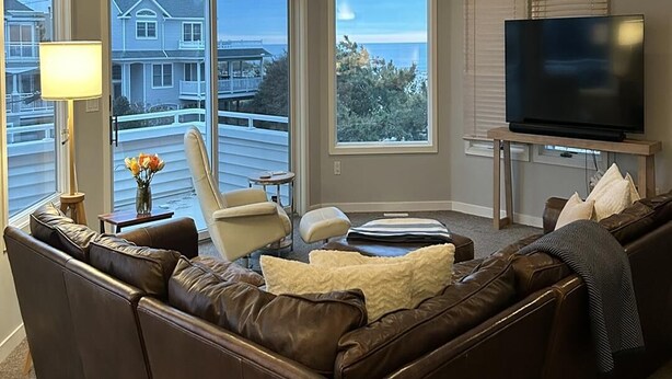 A living room with a brown leather sofa, a television, and a ceiling fan. - 4 bedroom accommodation in Harvey Cedars (Harvey Cedars)