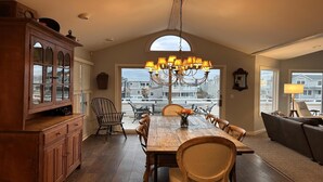 A spacious dining area with a high ceiling, a chandelier, and a view of the neighborhood through large windows. - 4 bedroom accommodation in Harvey Cedars (Harvey Cedars)