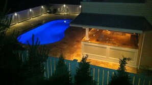 A swimming pool with a curved edge, a covered patio area, and a fenced backyard. - 4 bedroom accommodation in Harvey Cedars (Harvey Cedars)