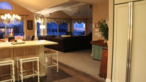 A living room with a sofa, a dining area with chairs, a kitchen with a refrigerator, and a view of the outside. - 4 bedroom accommodation in Harvey Cedars (Harvey Cedars)