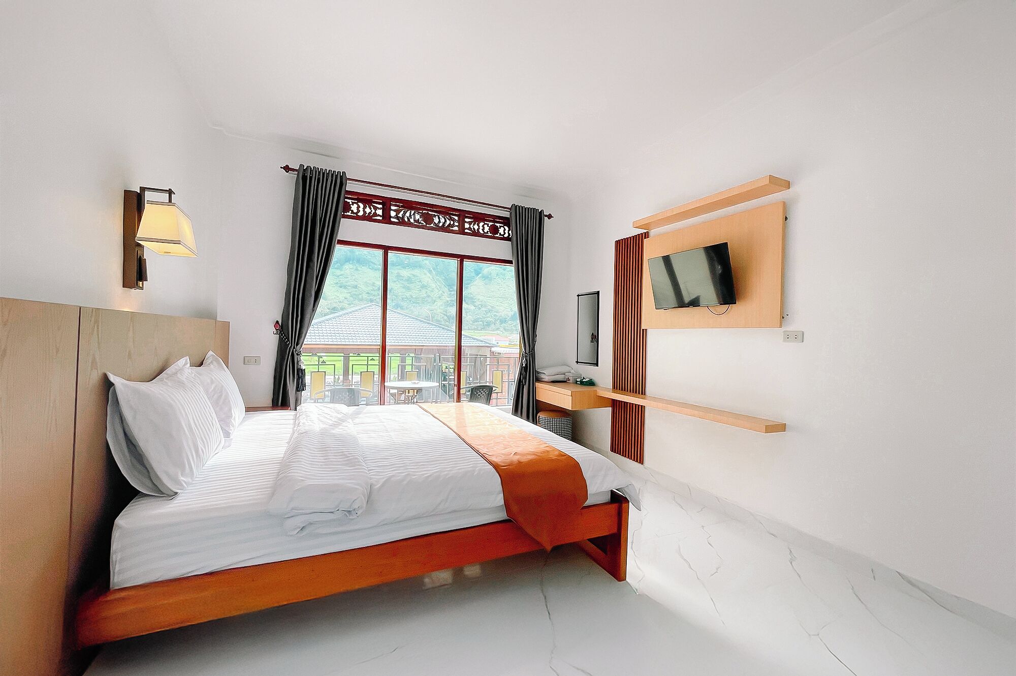 A modern hotel room with a large bed, a TV mounted on the wall, and a view of the outdoors.