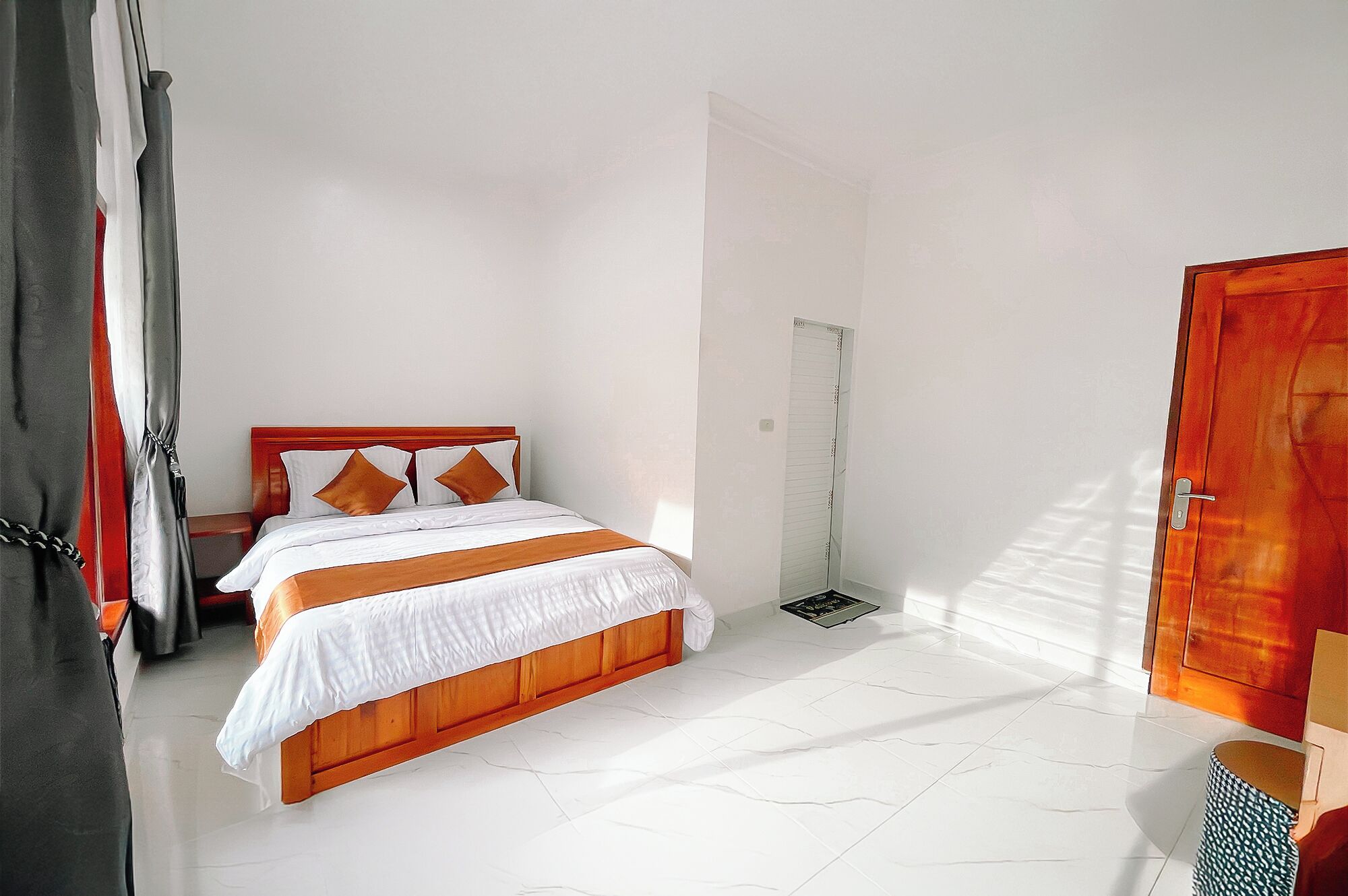 A hotel room with a wooden bed, white walls, and a tiled floor.