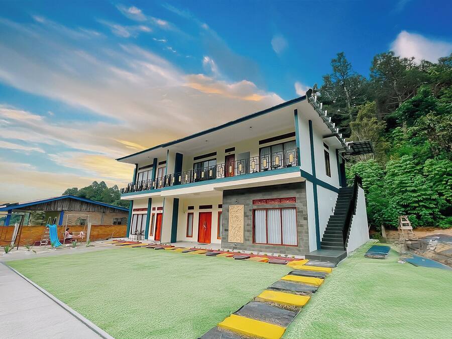 A two-story building with a balcony, a staircase, and a green lawn.