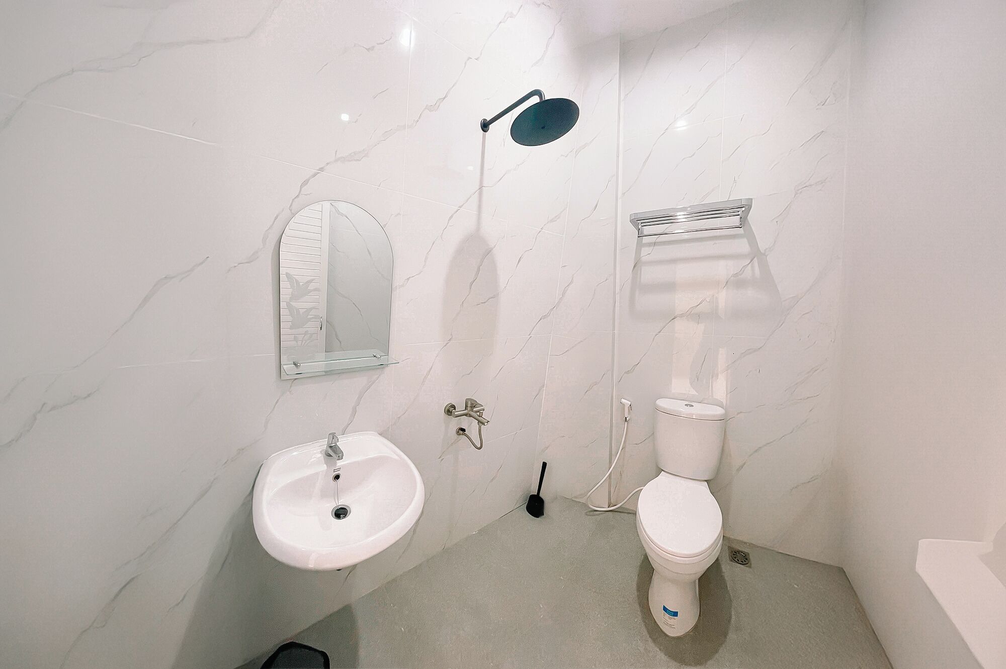 Un baño con lavamanos blanco, inodoro y ducha con cabezal de ducha de mano.