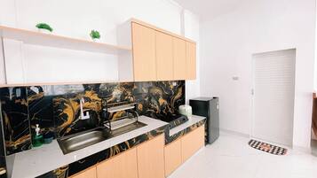 A modern kitchen with a black marble backsplash, wooden cabinets, and a black refrigerator.