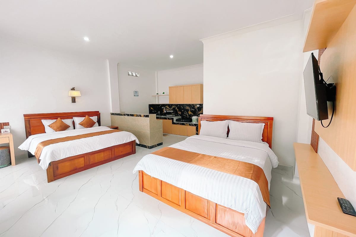 Quarto de hotel com duas camas, uma cozinha compacta, televisão e banheiro.