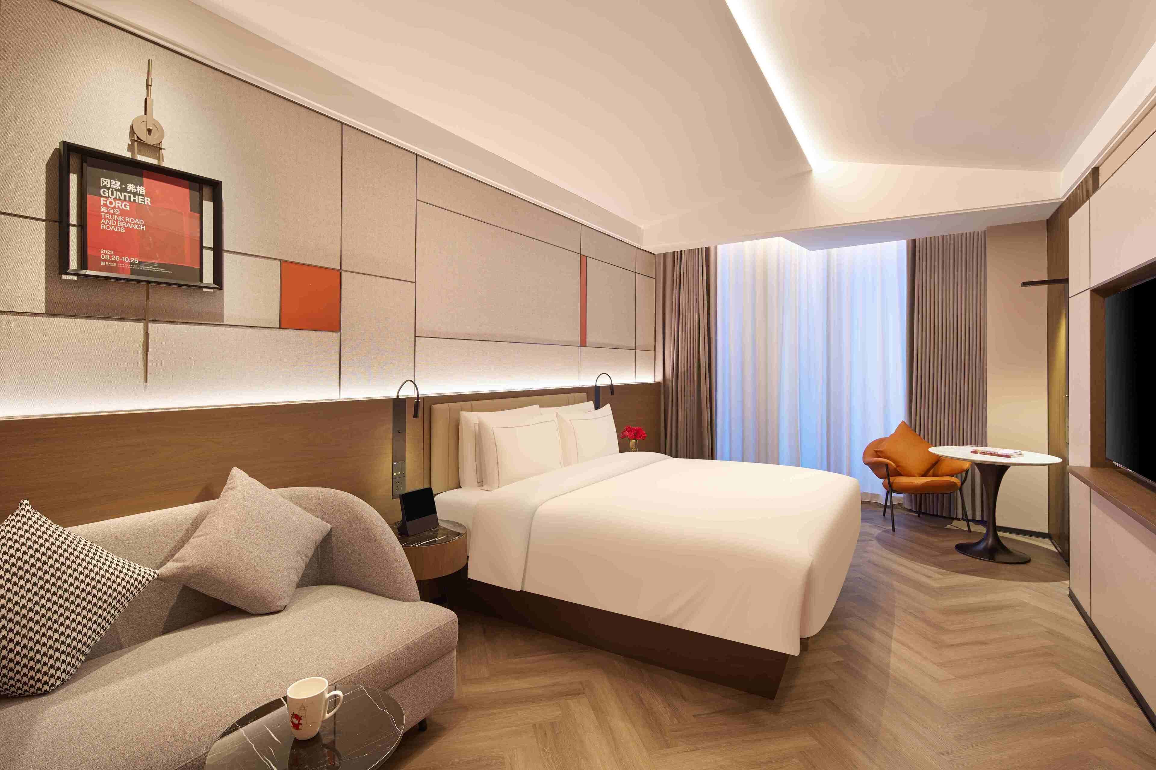 Ein Hotelzimmer mit Bett, Sofa, kleinem Tisch und Fernseher.